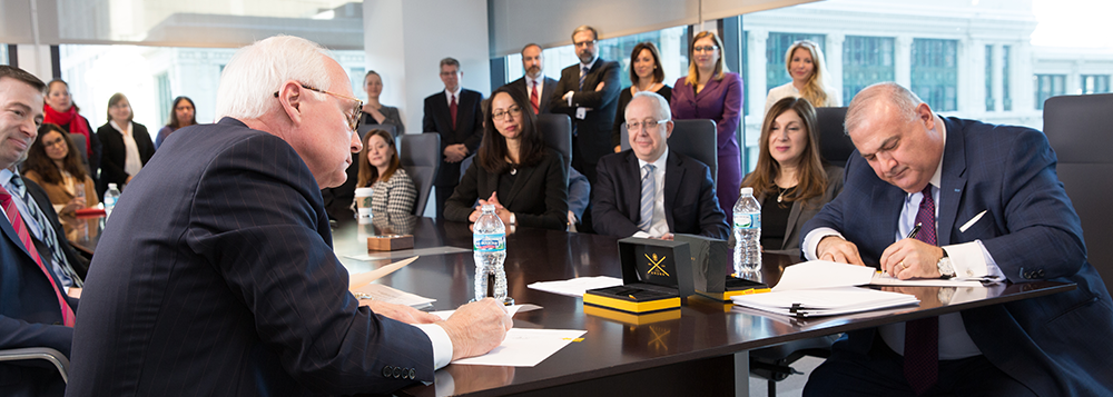 Bob Tannous and Bob Hermes signs the merger paperwork