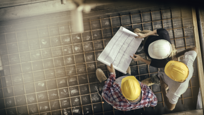 workers in hard hats looking at plans ensuring they are following the construction contract